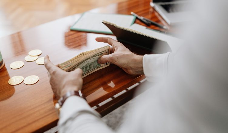 Person counting cash and coins on a wooden table, emphasizing financial tasks. — Sundry helpful tips for the beginners regard