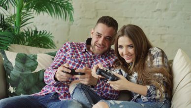 Happy couple enjoying video games together at home on a cozy sofa. — Take Advantage of Welcome Bonus Offers and Other Promoti