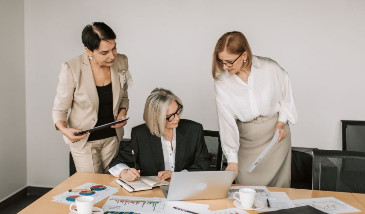 Three businesswomen discussing documents during a meeting in a modern office setting. — Take Control of Your Trades with the