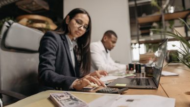 Two business professionals collaborating with a laptop and calculator in a modern office. — Tax Return and Your Choices