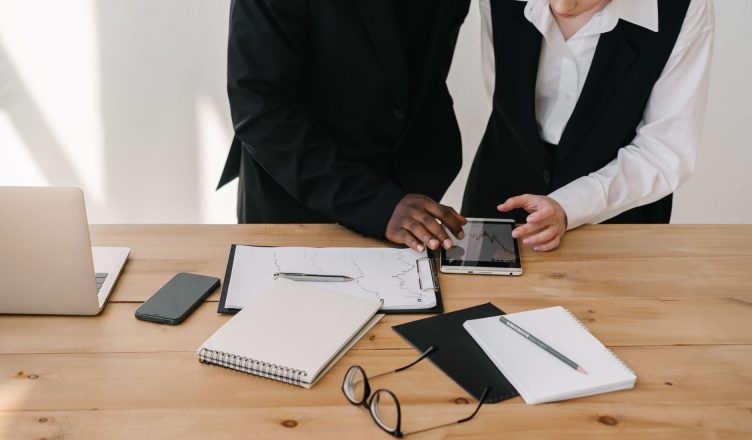 Two professionals collaborating over charts and tablet in a modern office setting. — The Beautiful Designs and Reviews