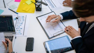 Team reviewing financial charts and digital data on tablets in an office setting. — The best way to choose the right business