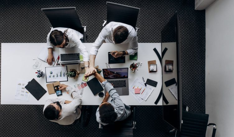 High angle view of colleagues collaborating around a conference table in a modern office setting. — The Current State of St.