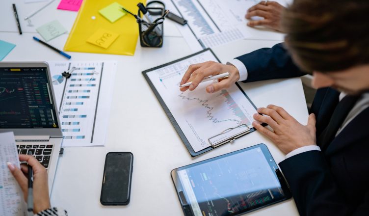 Team reviewing financial charts and digital data on tablets in an office setting. — The importance of putting up advertisemen