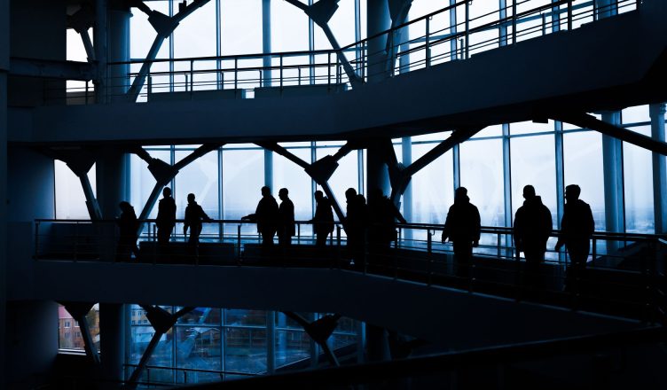 Silhouettes of people walking in a modern architectural building with large windows. — The industrial computer changes the ga