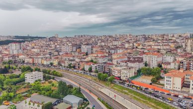 Aerial view of dense urban architecture with roads and greenery under cloudy skies. — The Right Amount of Risk in Trading For