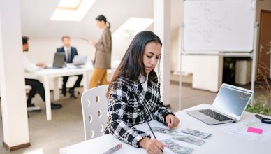 Focused businesswoman reviewing financial documents and currency in a modern office setting. — The rise of cryptocurrency tra