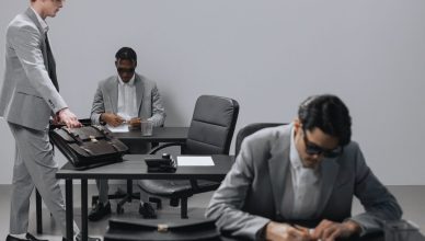 Business office with diverse employees in gray suits working at desks in an indoor setting. — The Truest Essentialities of Cl