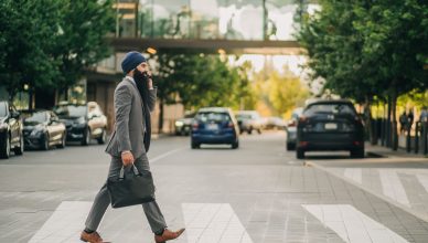 Sikh businessman with a turban crossing a city street on a zebra crossing, carrying a briefcase. — The world of online advert
