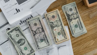 Stacks of US Dollar banknotes placed over financial documents and reports on a desk. — Various Home Loan Fees and Charges Tha