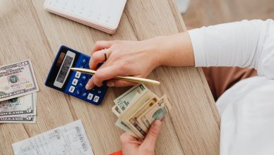 Person using a calculator and counting cash on a wooden table with receipts. — Vital Instructions For Forex Investing Success