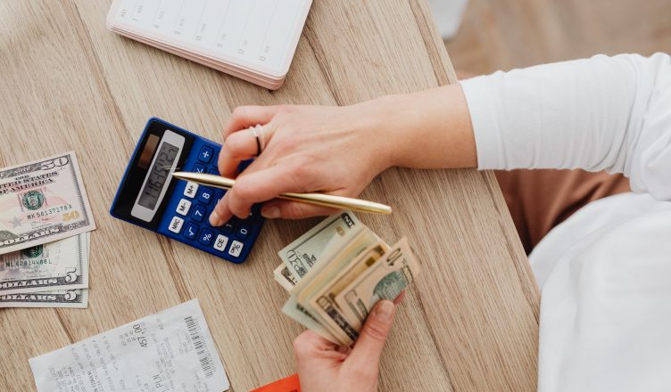 Person using a calculator and counting cash on a wooden table with receipts. — Vital Instructions For Forex Investing Success