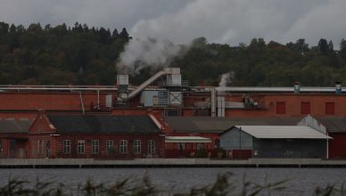 A factory with smoke emitting from chimneys along a river, surrounded by trees. — What Can I Do With a Belt Alignment Tool?