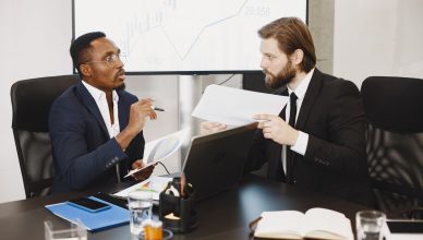 Two business professionals engaged in a planning meeting, discussing documents in a modern office setting. — What Characteriz