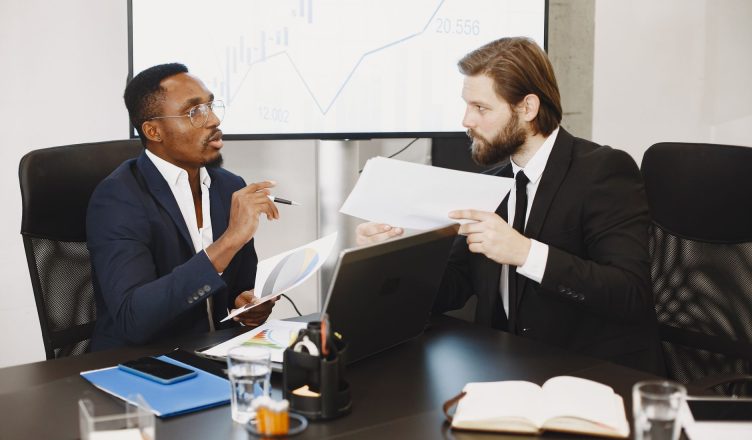 Two business professionals engaged in a planning meeting, discussing documents in a modern office setting. — What Characteriz