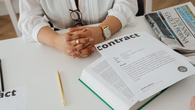 Businesswoman sitting at desk reviewing contract with legal documents and newspaper. — What to Look for When Searching for a