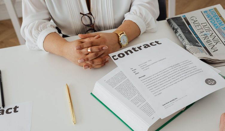 Businesswoman sitting at desk reviewing contract with legal documents and newspaper. — What to Look for When Searching for a