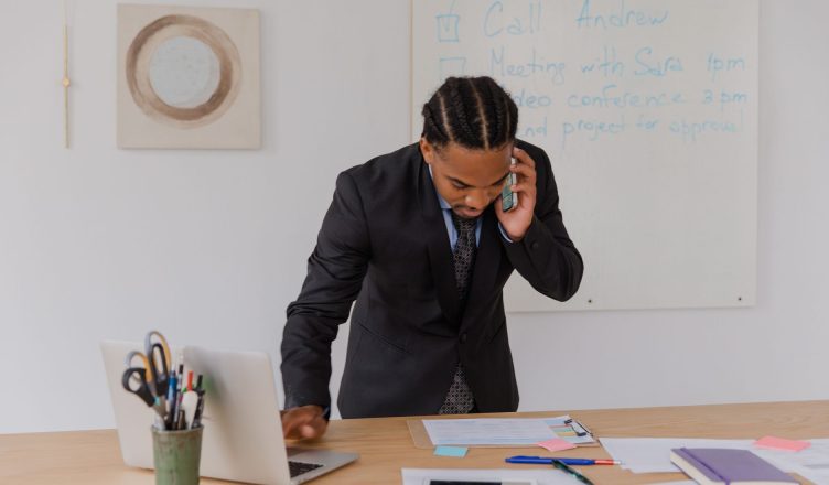 Professional businessman multitasking with phone and laptop at office desk, surrounded by documents. — What to look while cho