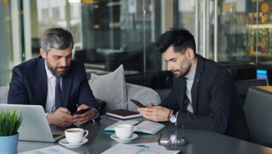 Two businessmen in a cafe working on smartphones and laptops, engaged in a meeting. — Why is the logo a must for branding obj
