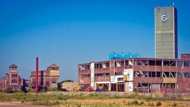 An old industrial factory building with a tower under a clear blue sky, showcasing urban decay. — Why should you hire a speak