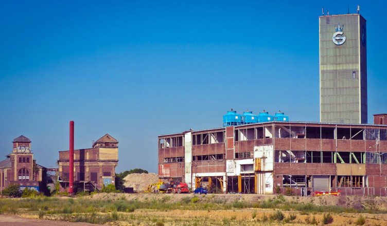 An old industrial factory building with a tower under a clear blue sky, showcasing urban decay. — Why should you hire a speak